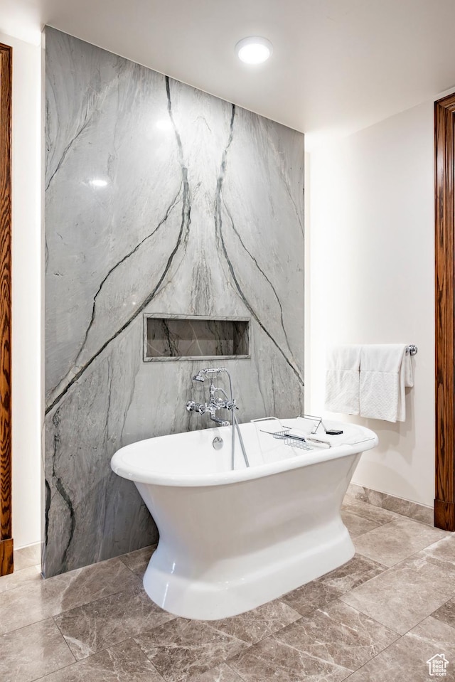 full bathroom with tile walls, marble finish floor, and a freestanding bath