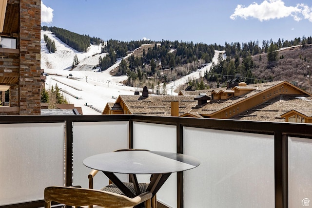 snow covered back of property with outdoor dining area and a mountain view