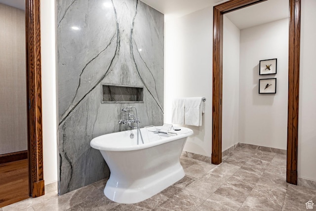bathroom with a soaking tub and baseboards