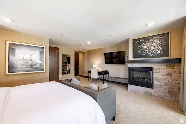 carpeted bedroom featuring a stone fireplace and recessed lighting