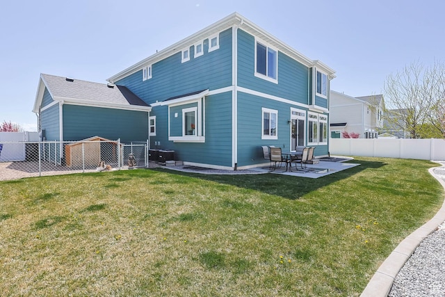 rear view of property featuring a yard, a patio, and a fenced backyard