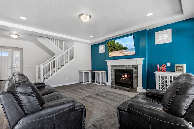 carpeted living room featuring stairway, a tray ceiling, and a textured ceiling