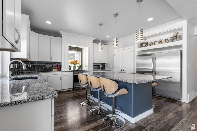 kitchen featuring stone countertops, a sink, a kitchen island, tasteful backsplash, and appliances with stainless steel finishes