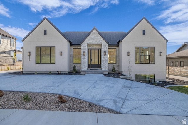 view of front of property featuring roof with shingles, stone siding, and stucco siding