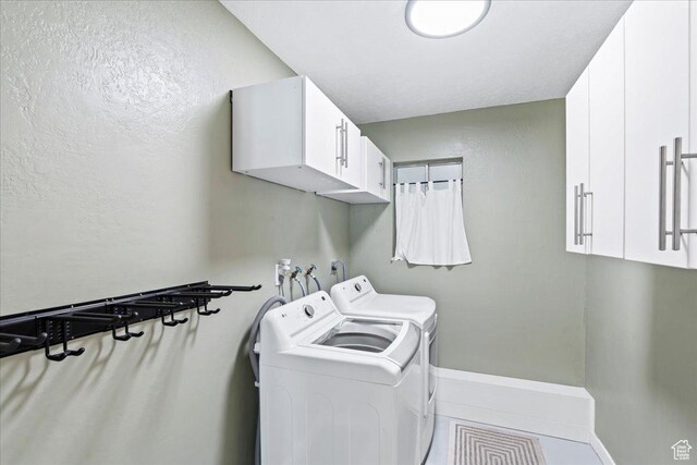 laundry area featuring washing machine and clothes dryer, cabinet space, tile patterned flooring, and baseboards