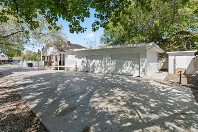 view of front facade featuring driveway, an outbuilding, a storage unit, and a garage