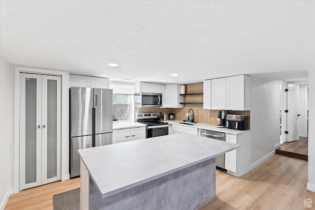 kitchen featuring white cabinetry, light wood finished floors, stainless steel appliances, and a sink