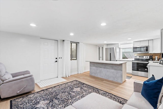 living room featuring baseboards, recessed lighting, and light wood-type flooring