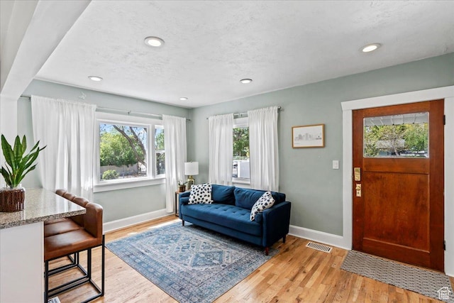 living area featuring light wood-style floors, visible vents, and baseboards