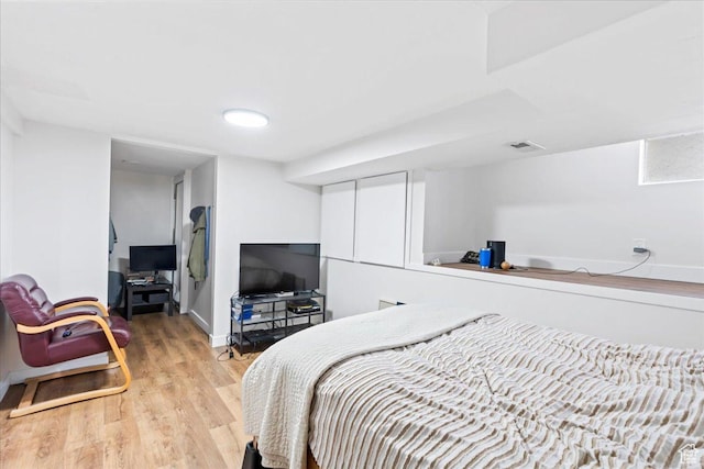 bedroom featuring light wood-type flooring, baseboards, and visible vents