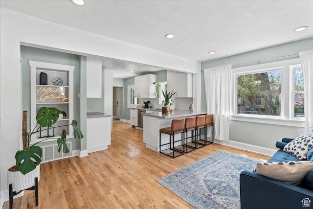 living room featuring baseboards, light wood-style floors, visible vents, and recessed lighting