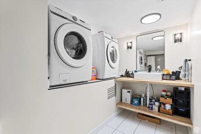 washroom featuring baseboards, tile patterned floors, a sink, and laundry area