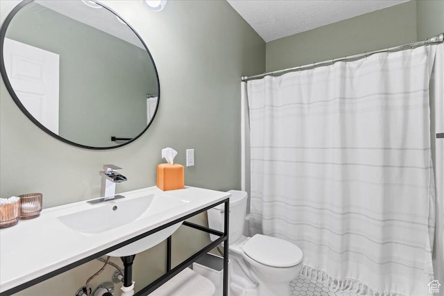full bath featuring toilet, tile patterned floors, a sink, and a textured ceiling