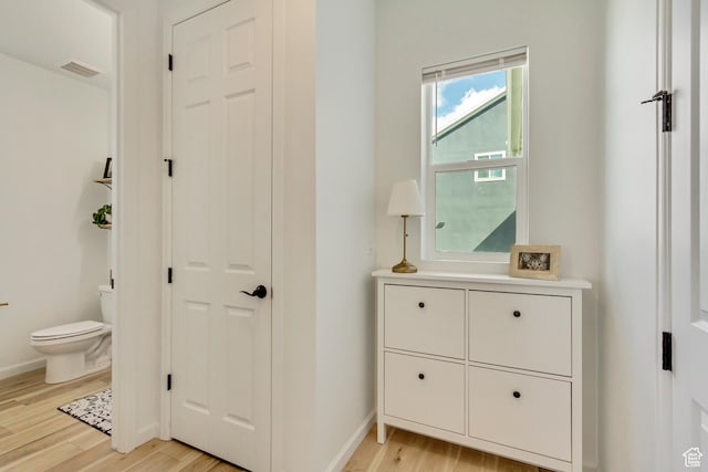 corridor featuring baseboards, light wood-style floors, and visible vents