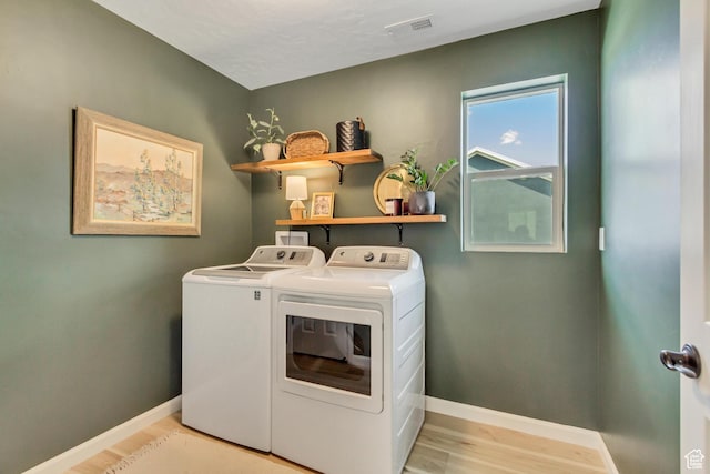 washroom featuring washing machine and dryer, light wood-style flooring, baseboards, and laundry area
