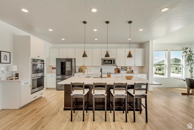 kitchen featuring stainless steel appliances, light countertops, a sink, and light wood-style floors