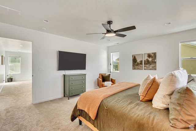 bedroom with ceiling fan, baseboards, light colored carpet, and multiple windows