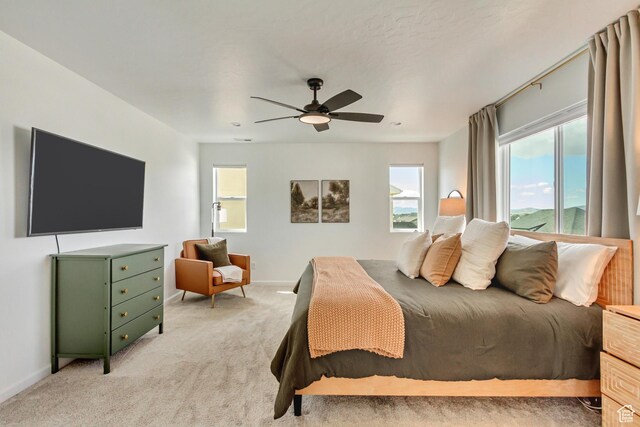 bedroom featuring light carpet, a ceiling fan, and baseboards