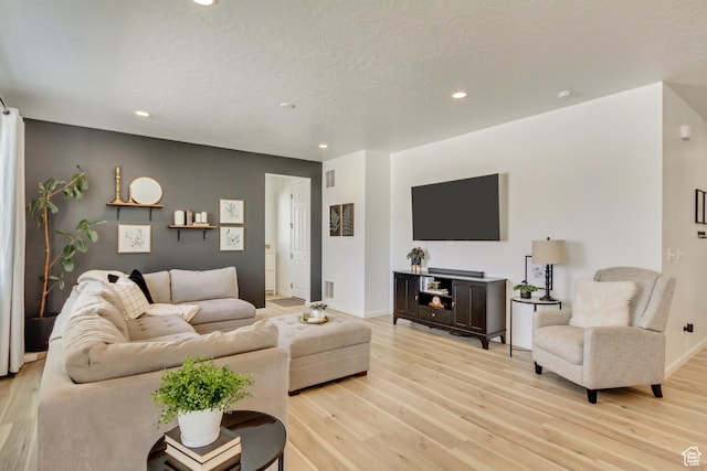 living room featuring baseboards, light wood-style flooring, visible vents, and recessed lighting