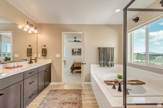 full bathroom with a bath, double vanity, ensuite bathroom, and a sink