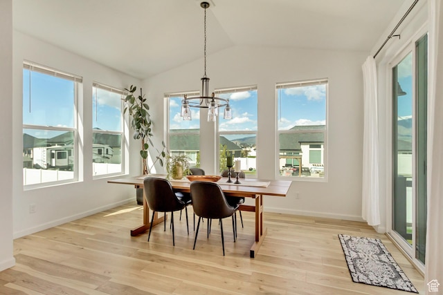 dining space featuring a chandelier, lofted ceiling, a wealth of natural light, and light wood-type flooring