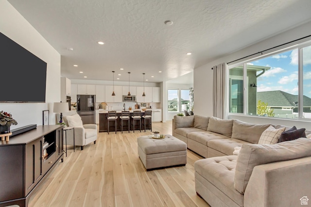 living area featuring light wood-style flooring, recessed lighting, and a textured ceiling