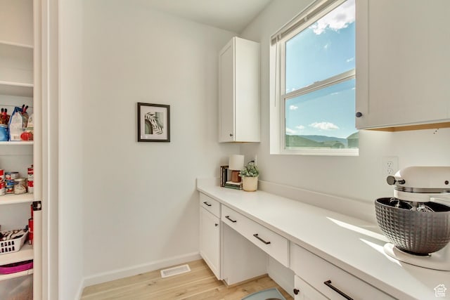 kitchen with white cabinets, light countertops, visible vents, and light wood-style floors