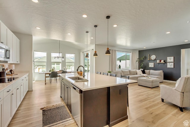 kitchen with light countertops, stainless steel appliances, light wood-type flooring, and a sink