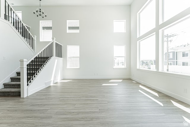 3677 W 950 N Unit 219, Lehi, UT 84043 - unfurnished living room with stairway, healthy amount of natural light, a chandelier, wood finished floors, and a towering ceiling