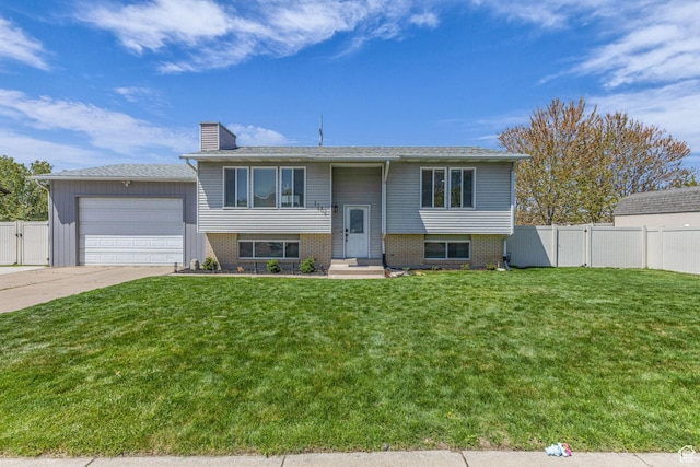 bi-level home featuring fence, a chimney, a front yard, and a garage