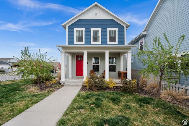 traditional-style home with stucco siding, a front lawn, fence, and covered porch