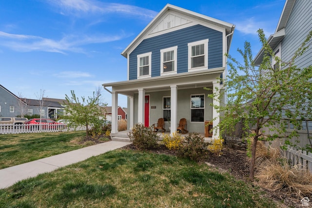 traditional-style house featuring a front lawn, fence, board and batten siding, and covered porch