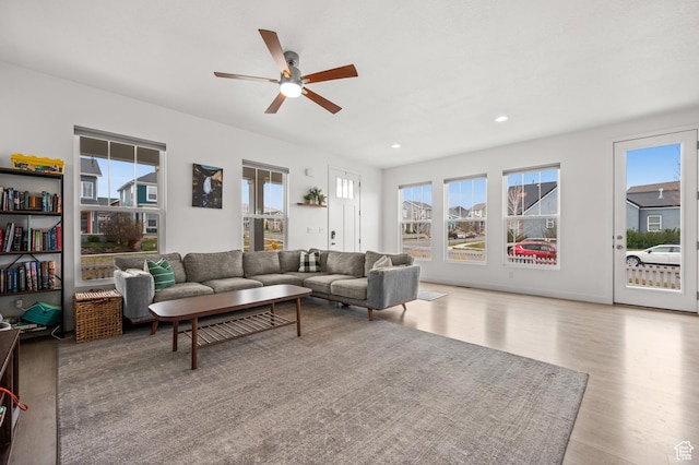 living area featuring wood finished floors, a wealth of natural light, and a ceiling fan