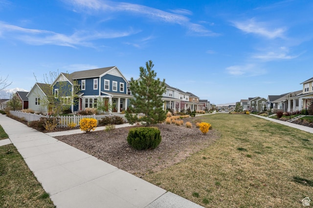 view of property's community featuring a residential view, a lawn, and fence