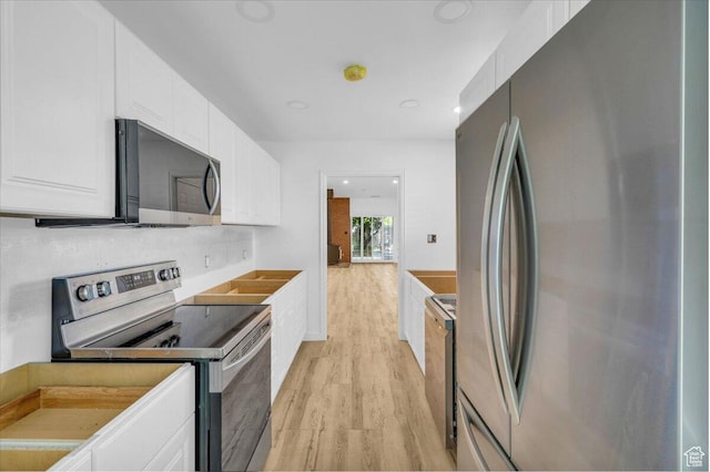 kitchen with white cabinetry, stainless steel appliances, and light wood-style floors