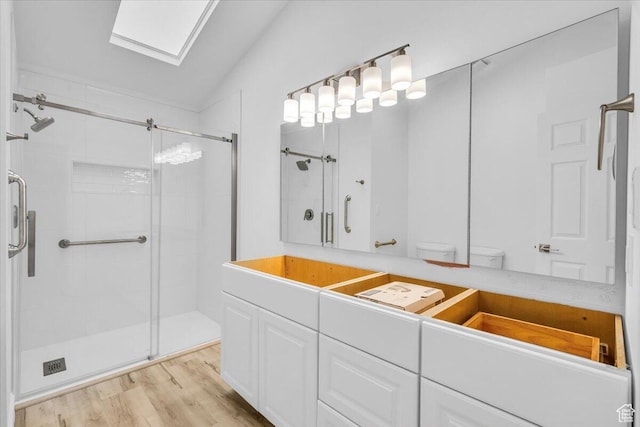 full bathroom featuring wood finished floors, lofted ceiling with skylight, and a shower stall