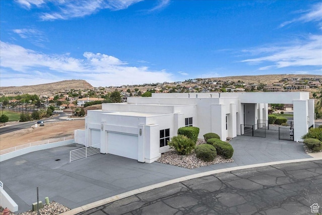 view of front of house with a gate, concrete driveway, stucco siding, a mountain view, and a garage