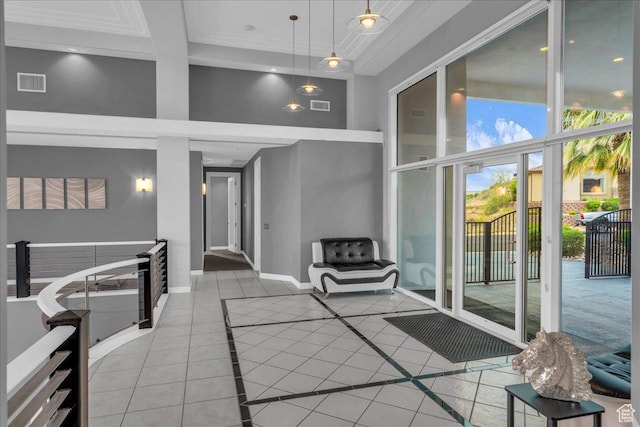 interior space featuring light tile patterned flooring, visible vents, a towering ceiling, and baseboards