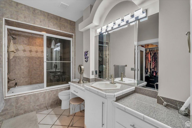 bathroom with tile patterned floors, a walk in closet, vanity, tiled shower / bath combo, and visible vents