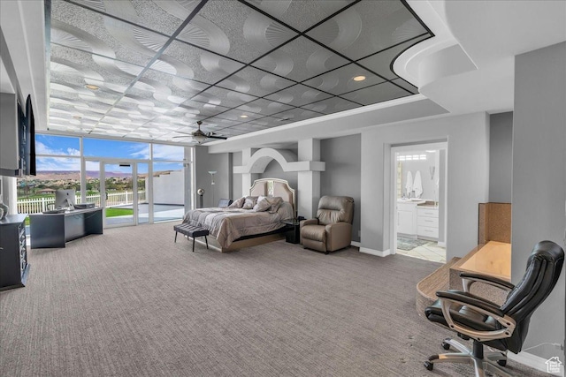 carpeted bedroom with baseboards, ensuite bath, floor to ceiling windows, and multiple windows