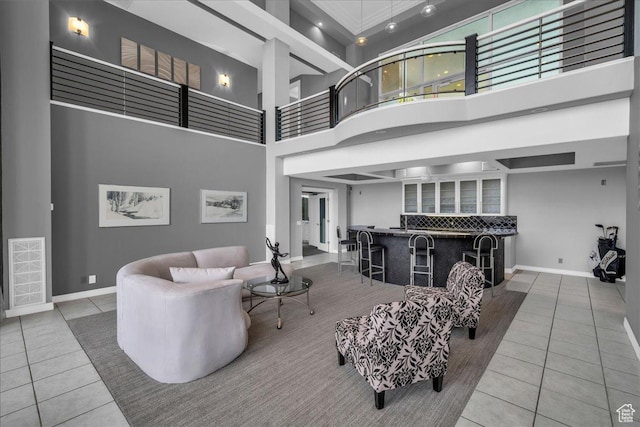 living room featuring indoor bar, a high ceiling, tile patterned flooring, and baseboards