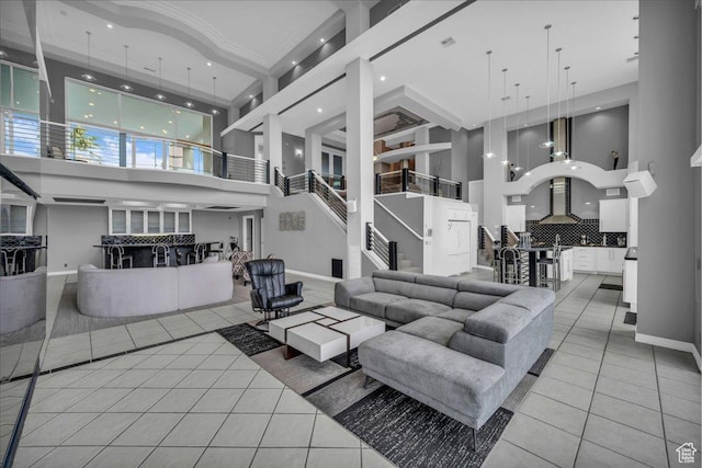 living area with baseboards, light tile patterned flooring, and a towering ceiling