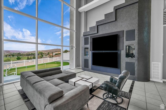living room with tile patterned floors, baseboards, visible vents, and a high ceiling