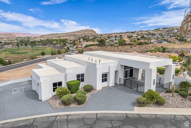 view of front of home featuring a mountain view, a gate, concrete driveway, fence, and stucco siding