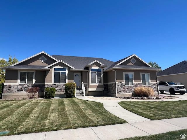 craftsman-style home with stucco siding, stone siding, and a front yard