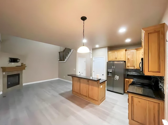 kitchen with dark countertops, a center island, tasteful backsplash, open floor plan, and appliances with stainless steel finishes