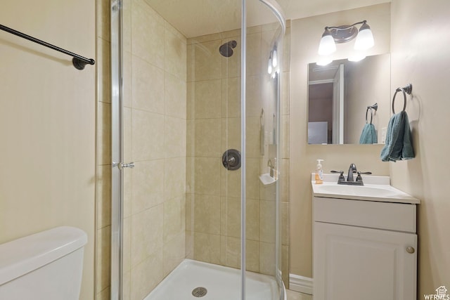 bathroom with a shower stall, toilet, and vanity