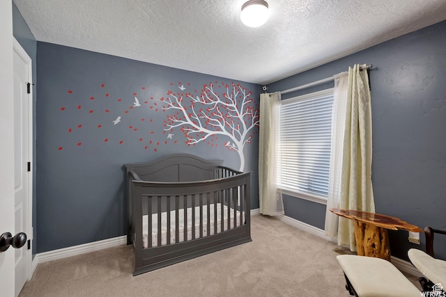 carpeted bedroom featuring a nursery area, baseboards, and a textured ceiling