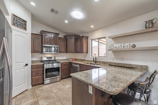 1024 Painted Cloud Pl, Washington, UT 84780 - kitchen featuring vaulted ceiling, a kitchen breakfast bar, a sink, stainless steel appliances, and a peninsula