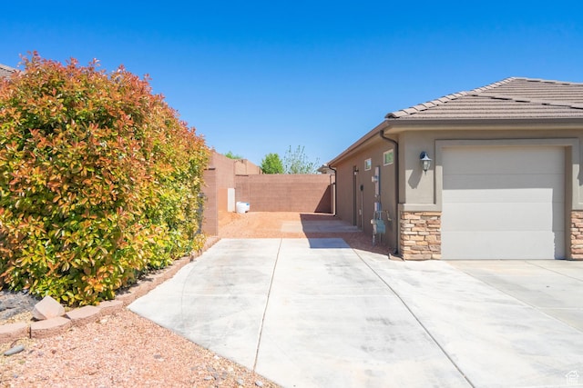 1024 Painted Cloud Pl, Washington, UT 84780 - view of side of home with a fenced backyard, concrete driveway, an attached garage, stucco siding, and stone siding